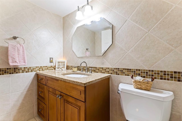 bathroom with toilet, vanity, and tile walls