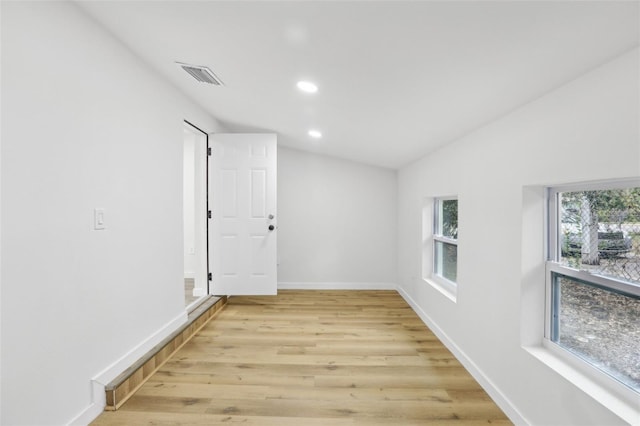 empty room with light hardwood / wood-style floors and vaulted ceiling