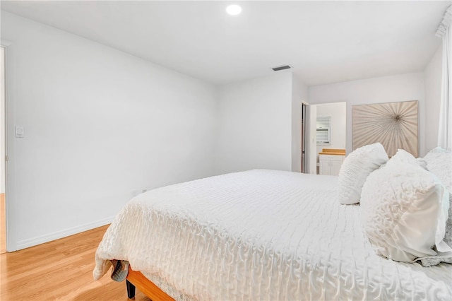 bedroom featuring hardwood / wood-style flooring and connected bathroom