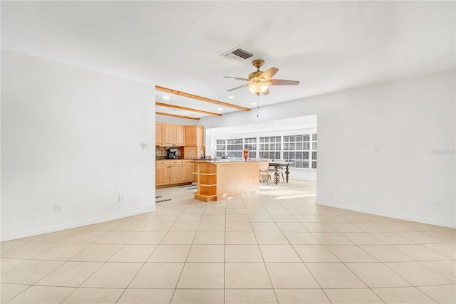 unfurnished living room with beamed ceiling, ceiling fan, and light tile patterned floors