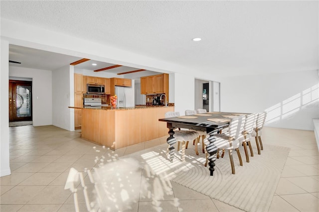 dining space with light tile patterned flooring, beam ceiling, and sink