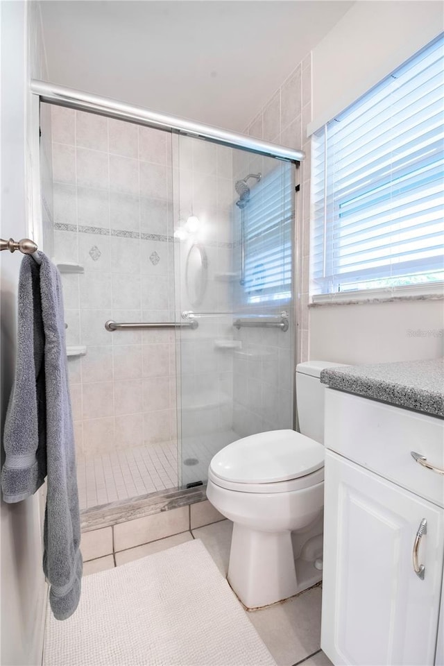 bathroom with tile patterned flooring, vanity, toilet, and walk in shower