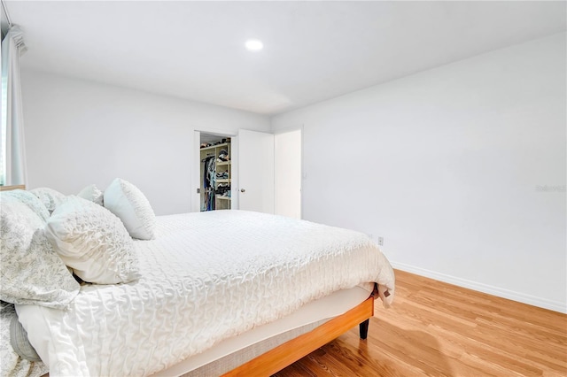 bedroom featuring a spacious closet, hardwood / wood-style floors, and a closet