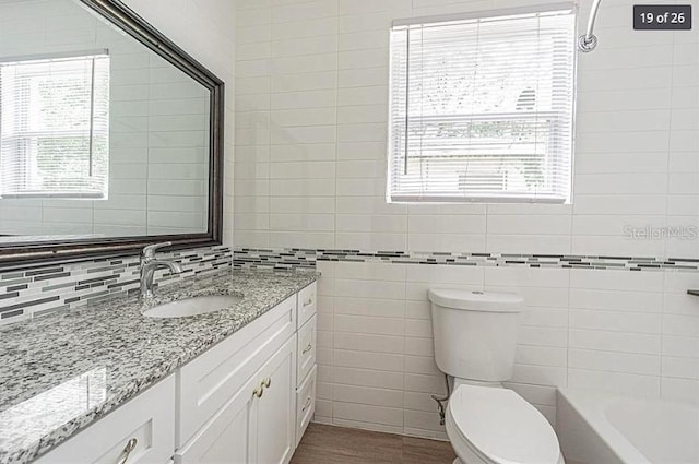 bathroom featuring toilet, wood-type flooring, a healthy amount of sunlight, and vanity