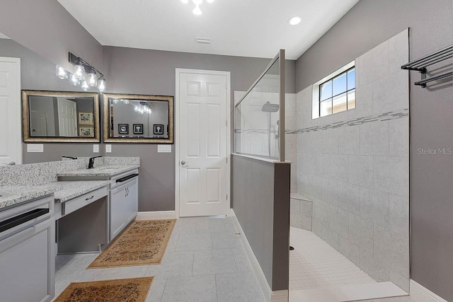 bathroom featuring vanity, tile patterned flooring, and tiled shower