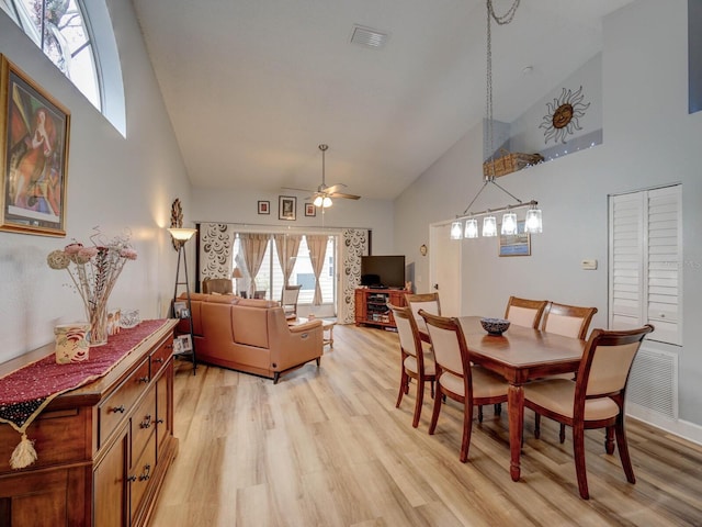 dining area with ceiling fan, high vaulted ceiling, and light hardwood / wood-style floors