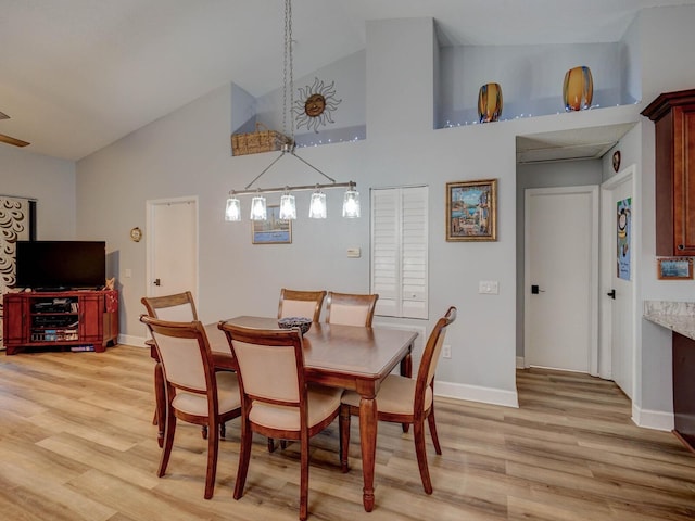 dining space with light wood-type flooring and high vaulted ceiling