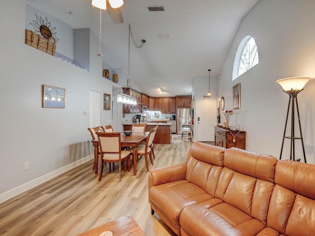 living room with light hardwood / wood-style floors, a high ceiling, and ceiling fan