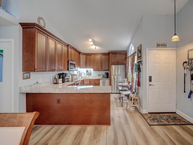 kitchen featuring pendant lighting, kitchen peninsula, sink, light hardwood / wood-style flooring, and stainless steel appliances