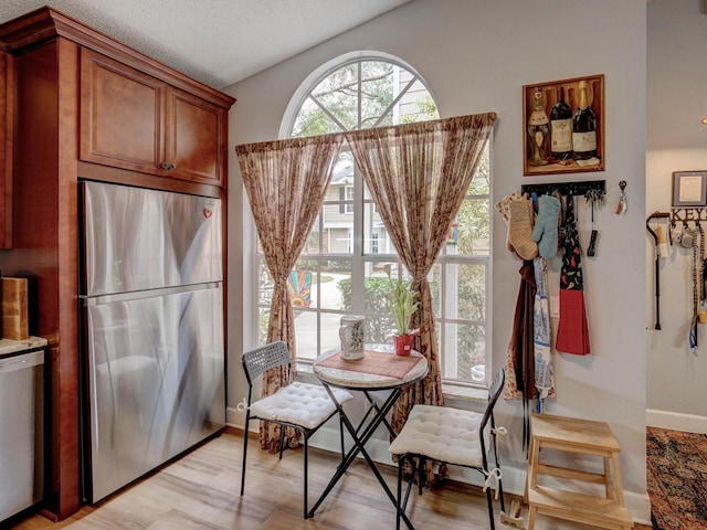 dining space with a textured ceiling and light hardwood / wood-style floors