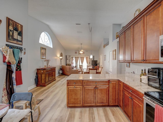 kitchen with ceiling fan, light hardwood / wood-style flooring, kitchen peninsula, and light stone countertops