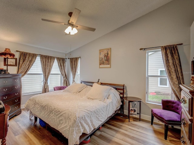 bedroom with ceiling fan, vaulted ceiling, multiple windows, and light hardwood / wood-style flooring