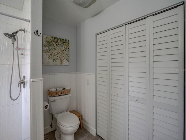 bathroom with toilet, hardwood / wood-style floors, and tiled shower