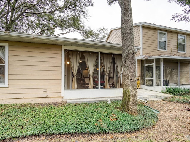 view of side of home with a sunroom and a patio