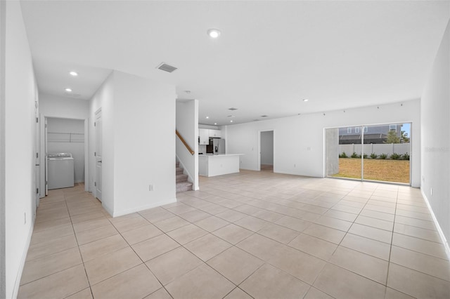 unfurnished living room with washer / clothes dryer and light tile patterned floors