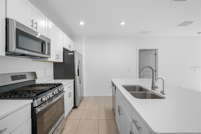 kitchen featuring stainless steel appliances, a kitchen island with sink, light tile patterned flooring, white cabinets, and sink