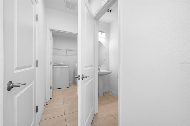 bathroom with washer and dryer, sink, and tile patterned floors