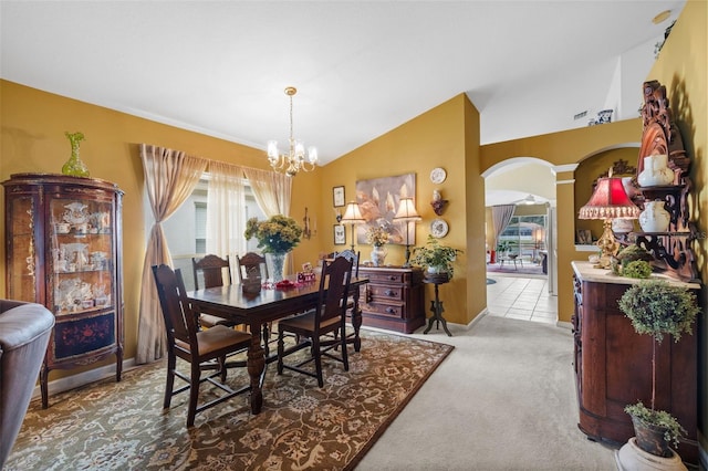 dining space with arched walkways, a notable chandelier, lofted ceiling, light colored carpet, and baseboards