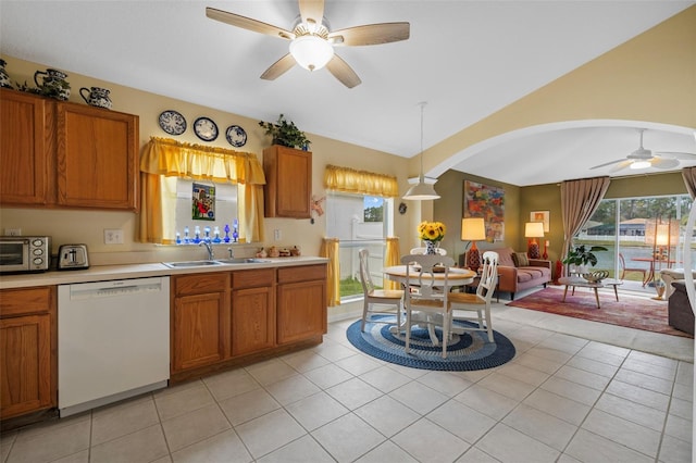 kitchen featuring white dishwasher, a sink, vaulted ceiling, light countertops, and brown cabinets