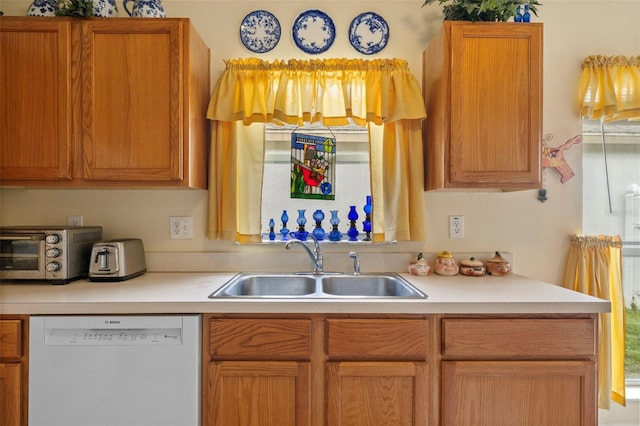 kitchen with a toaster, light countertops, white dishwasher, and a sink