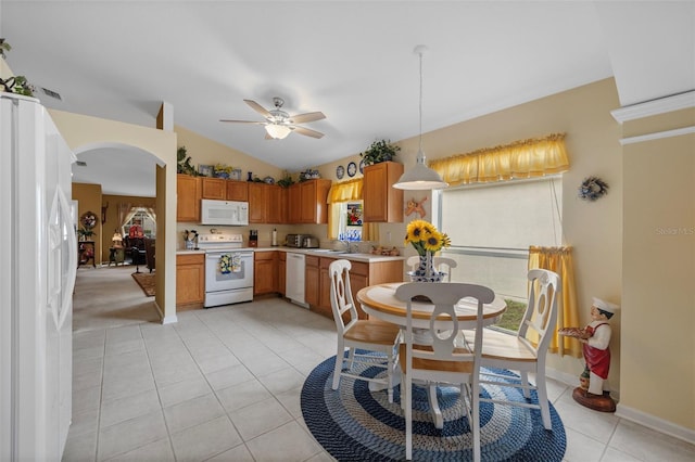 kitchen with lofted ceiling, light tile patterned floors, arched walkways, white appliances, and light countertops