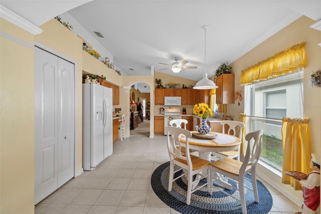 dining room featuring arched walkways, light tile patterned flooring, visible vents, a ceiling fan, and vaulted ceiling