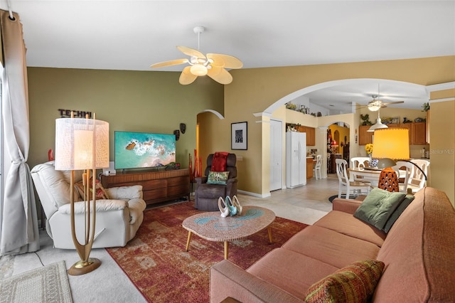 living room featuring a ceiling fan, arched walkways, and vaulted ceiling