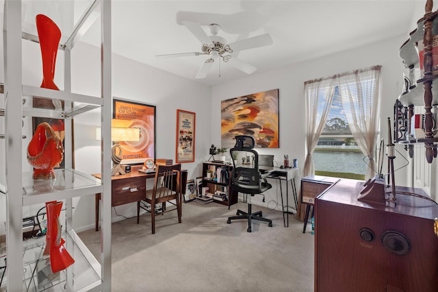 office space featuring light carpet, a water view, and ceiling fan