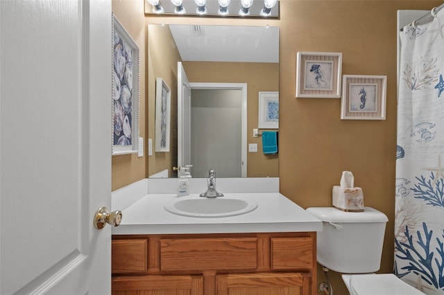 bathroom featuring curtained shower, vanity, and toilet