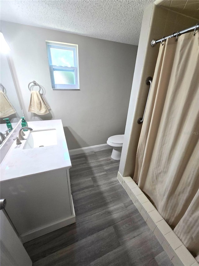 bathroom with a textured ceiling, a shower with shower curtain, vanity, and toilet