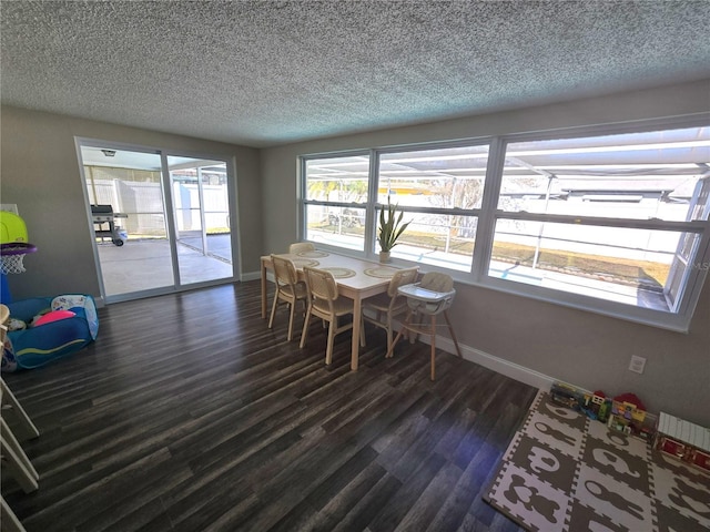 dining area with dark wood-type flooring, a textured ceiling, and a wealth of natural light