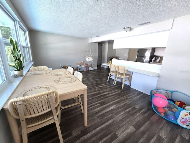 dining space featuring a textured ceiling and dark wood-type flooring