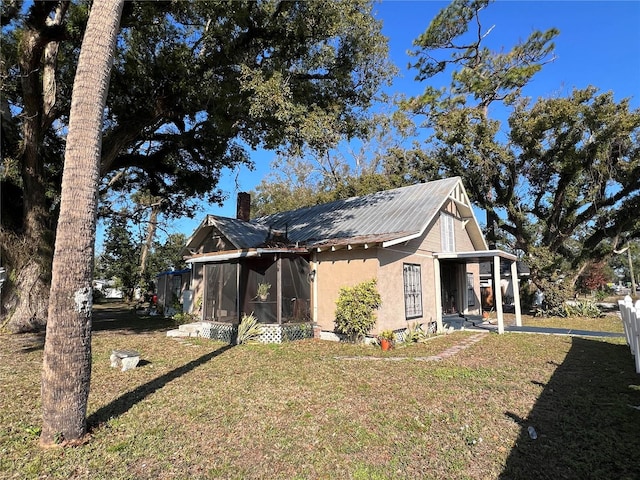 view of side of property featuring a yard, a carport, and a sunroom