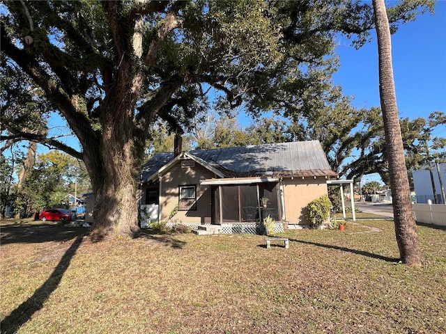 rear view of property featuring a sunroom and a lawn