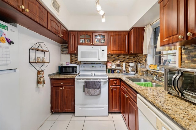 kitchen with decorative backsplash, sink, white appliances, light stone countertops, and light tile patterned floors