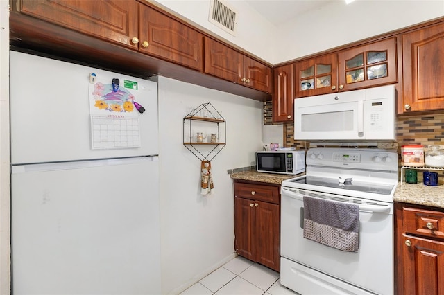 kitchen with light tile patterned floors, decorative backsplash, light stone counters, and white appliances