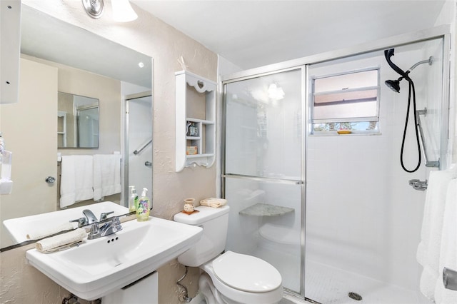 bathroom featuring sink, toilet, and a shower with door