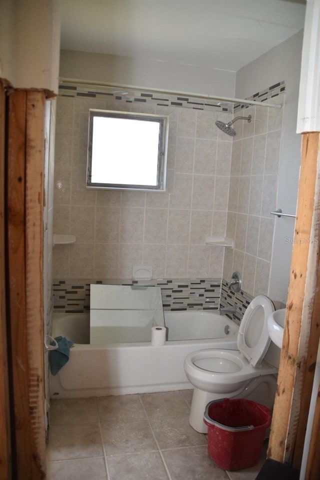 bathroom featuring toilet, tiled shower / bath combo, and tile patterned floors