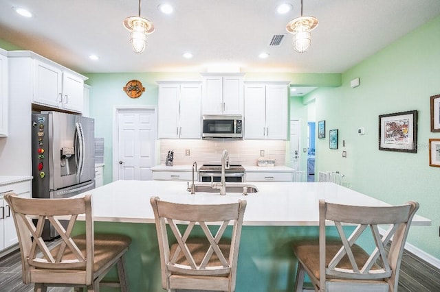 kitchen with decorative light fixtures, white cabinets, sink, and stainless steel appliances