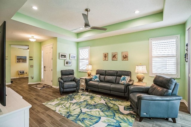 living room with ceiling fan and a raised ceiling