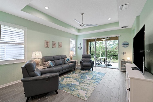 living room featuring ceiling fan and a tray ceiling