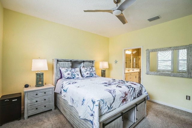 bedroom with ceiling fan, ensuite bathroom, and carpet flooring