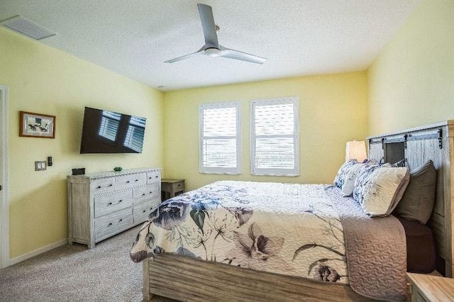 carpeted bedroom with ceiling fan and a textured ceiling