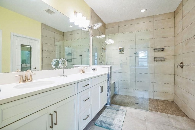 bathroom featuring vanity, tile patterned floors, and tiled shower