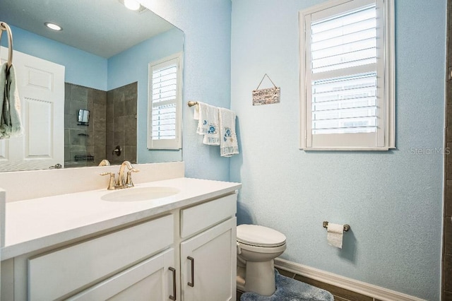 bathroom featuring toilet, vanity, and a tile shower