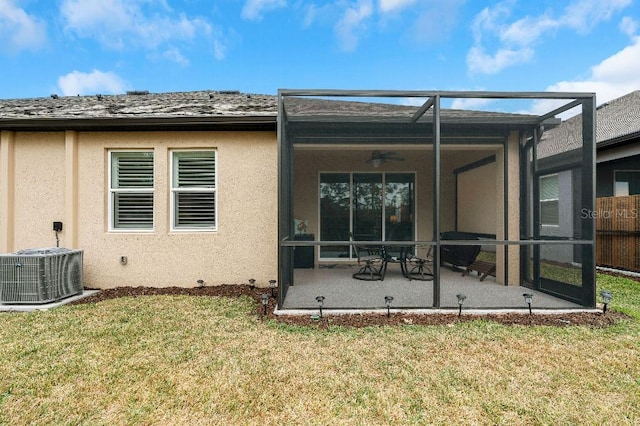 back of house with ceiling fan, a patio area, a yard, glass enclosure, and central AC unit