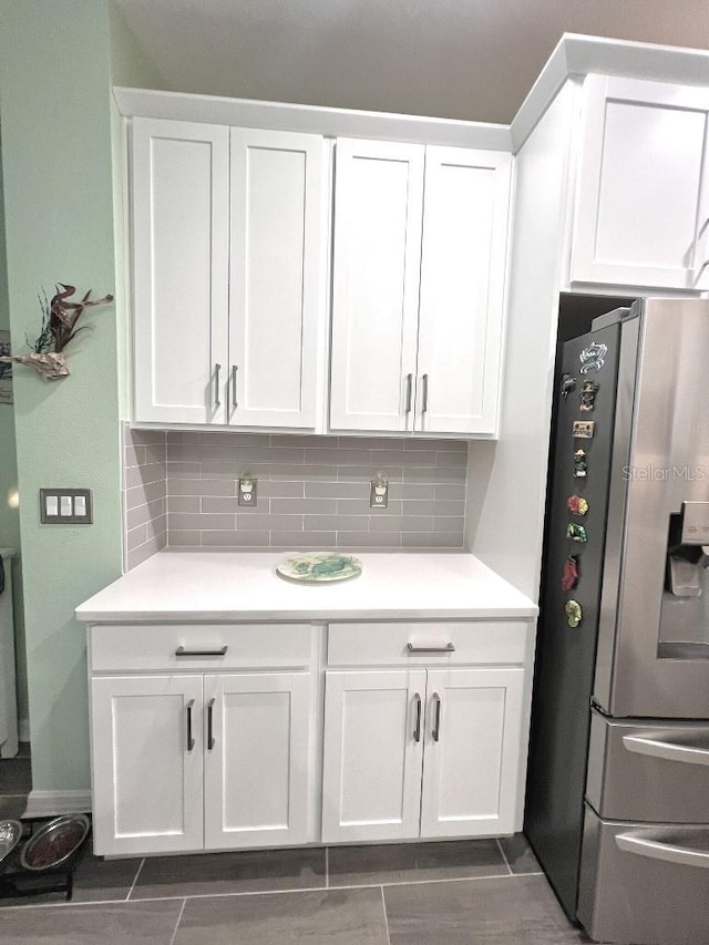 kitchen featuring white cabinets, stainless steel fridge with ice dispenser, and tasteful backsplash