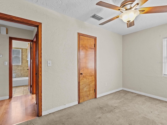 unfurnished bedroom featuring a textured ceiling, ceiling fan, light carpet, and multiple windows