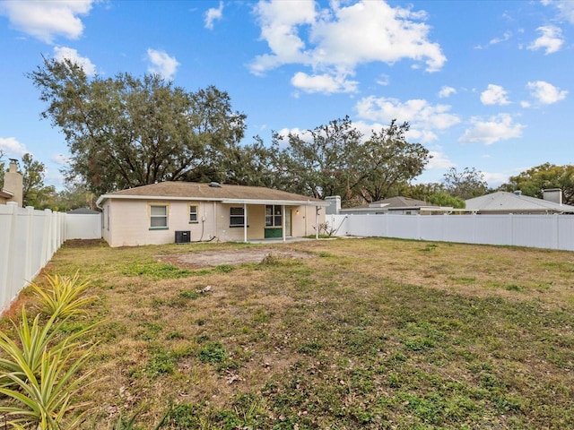 back of house with a yard and central AC