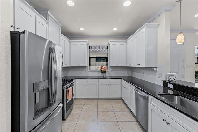 kitchen featuring white cabinetry, stainless steel appliances, hanging light fixtures, ornamental molding, and light tile patterned floors